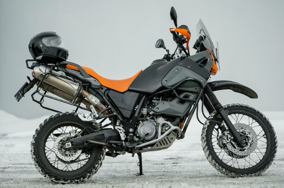 black and yellow motorcycle standing on a white field with hills behind