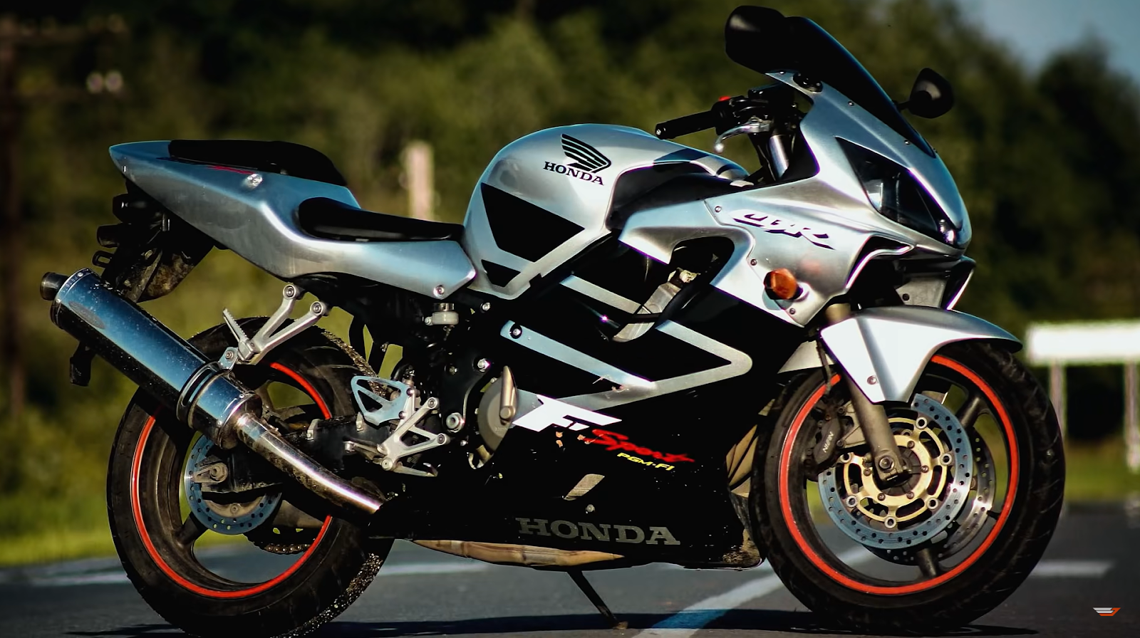 Honda CBR600RR - silver and black bike in front of blurred road and trees