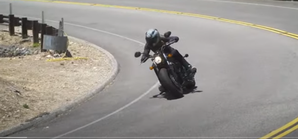 a person in a helmet riding a roadster on the road